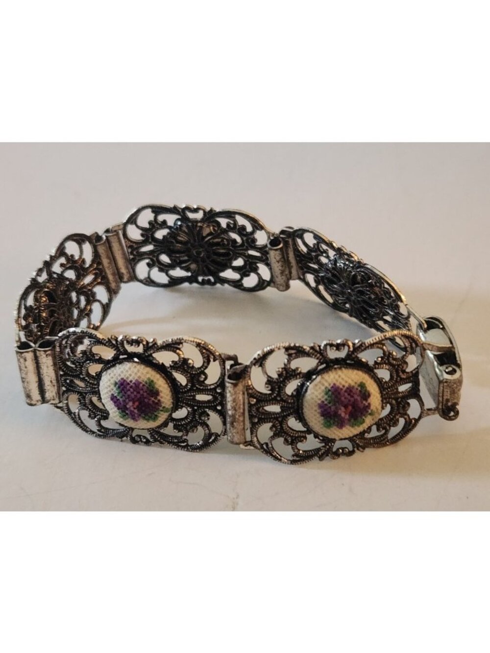 silver-tone link bracelet featuring ornate filigree metalwork and textured caboc